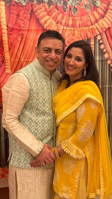 Ankur and Soumya in yellow in front of a marigold backdrop